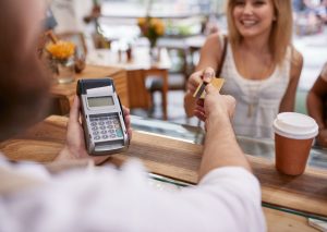 Young lady paying for a coffee using her credit card