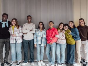 Lots of different teenagers in a line together in front of a wall
