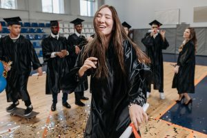 Year 12 girl dancing and celebrating in black graduation robs.